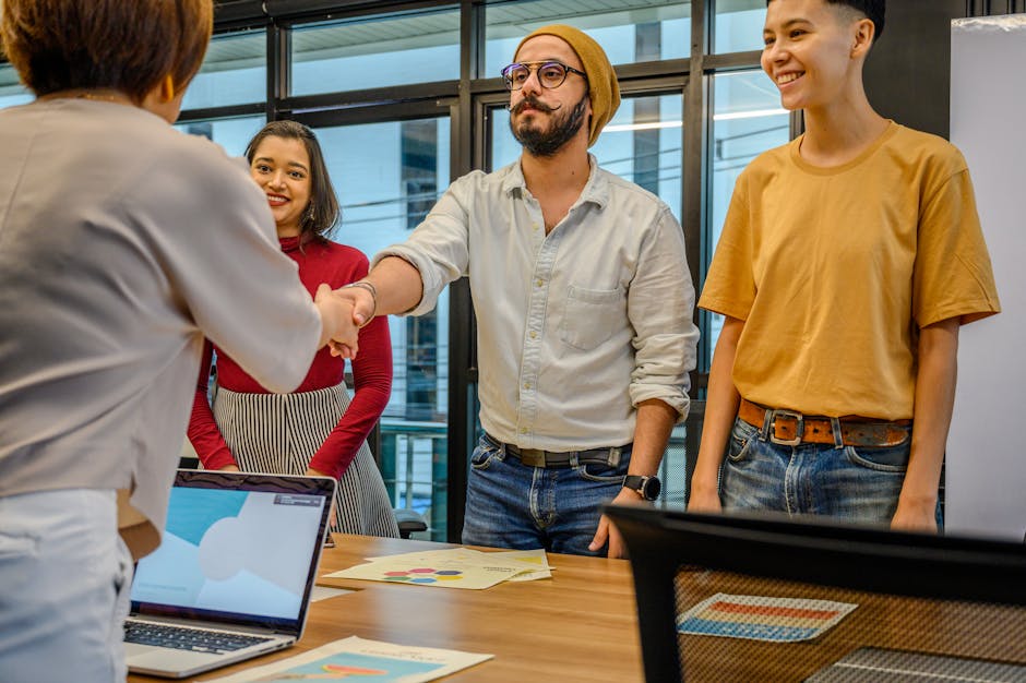 Colleagues shaking hands during a business meeting in a modern office setting.